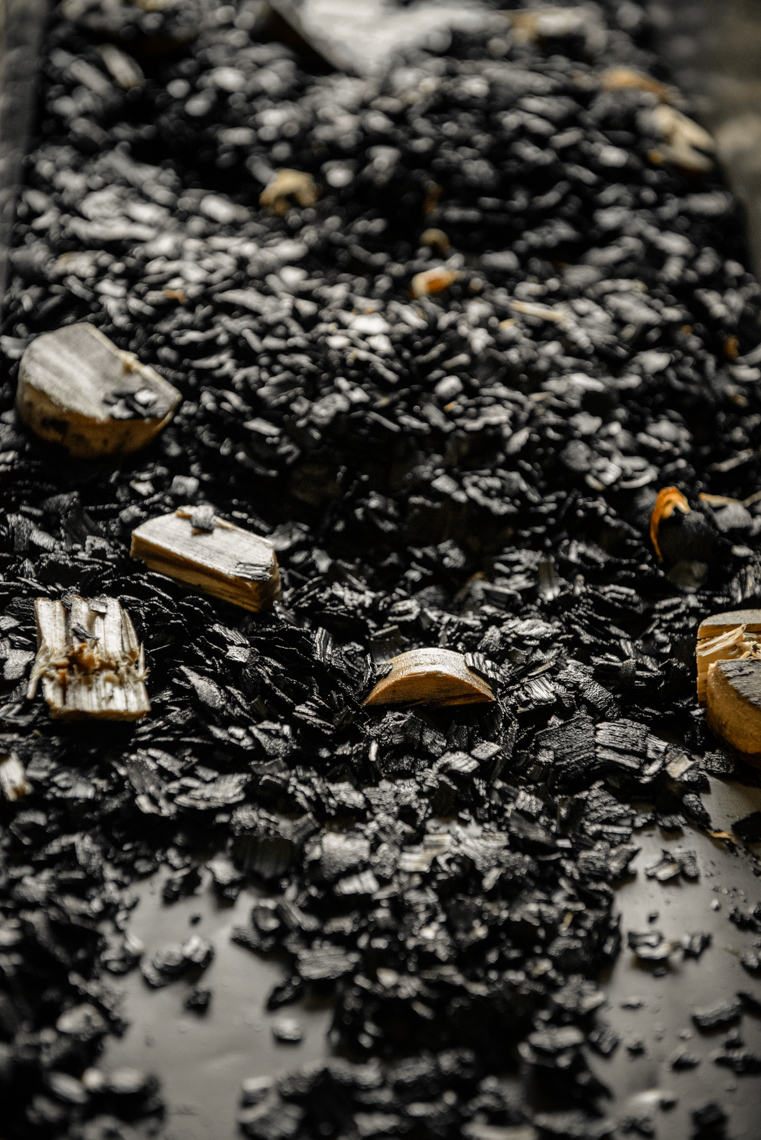 Bits of aged charcoal and wooden plugs lay in a trough after a whiskey barrel was dumped at George Dickel Distillery. Rights managed stock photograph by Nashville Photographer Kristina Krug.