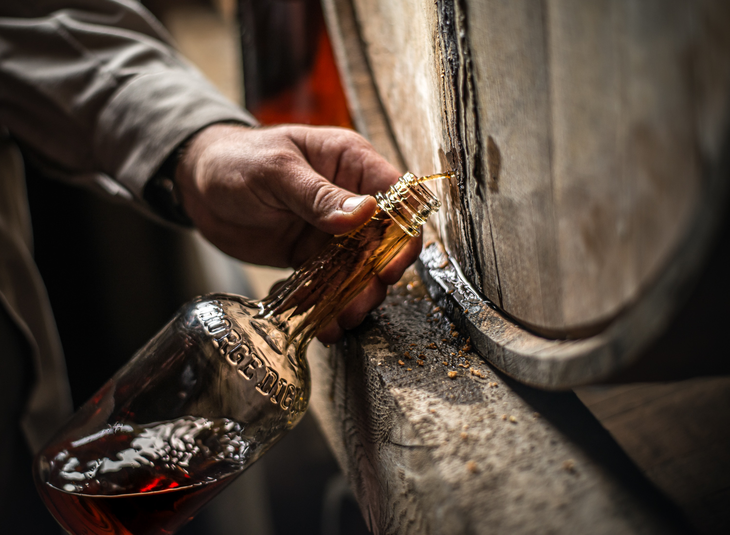 A worker collects a sample of barrel-aged hand-crafted whiskey from an aged barrel at George Dickel Tennessee Whisky Distillery by Nashville Editorial and Beverage Photographer Kristina Krug