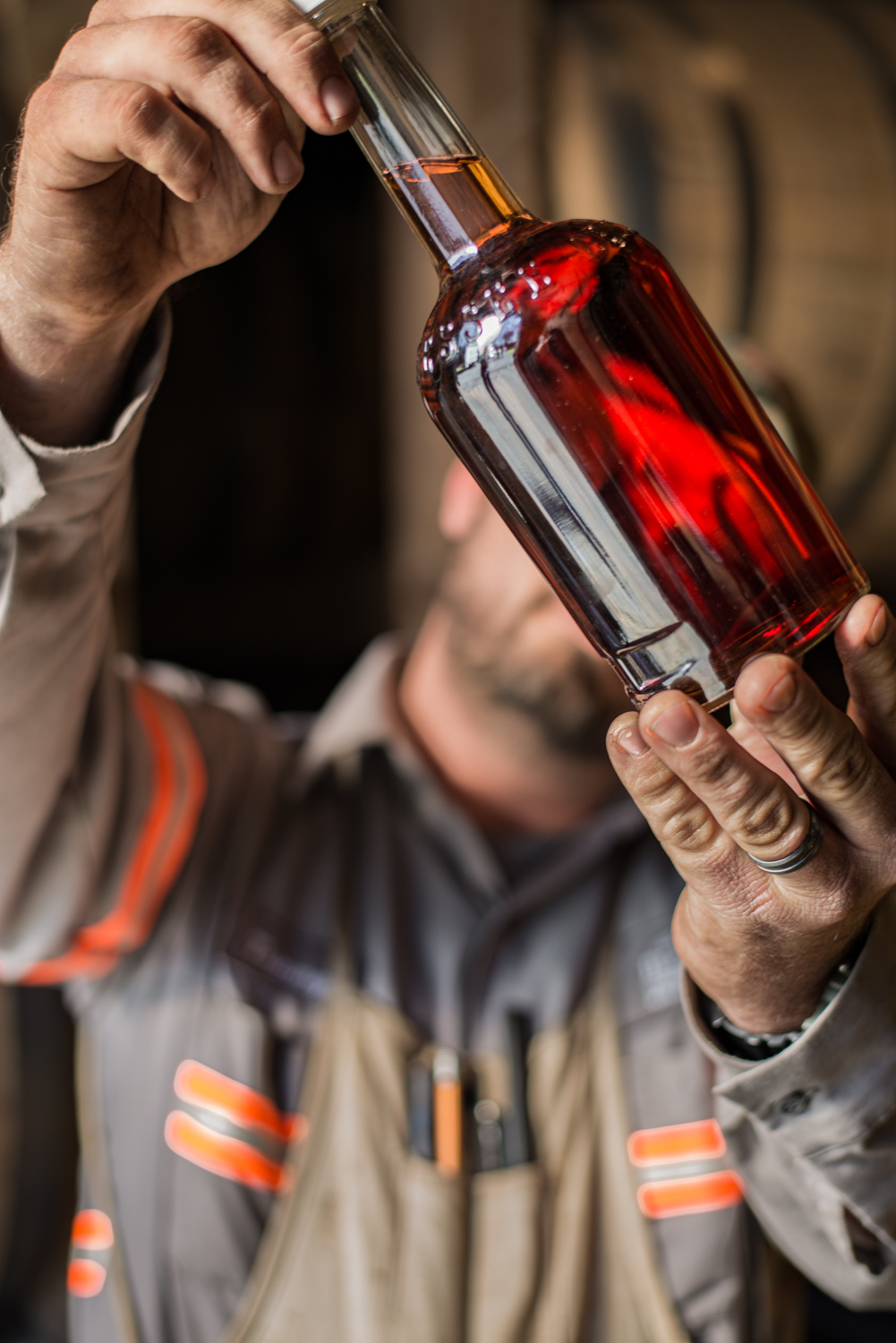 A distillery worker holding bottle of sampled whiskey at George Dickel Distillery, showing grit, hard work, craftsmanship. Photo by Nashville and Chicago editorial, industrial, beverage, and product photographer Kristina Krug. 