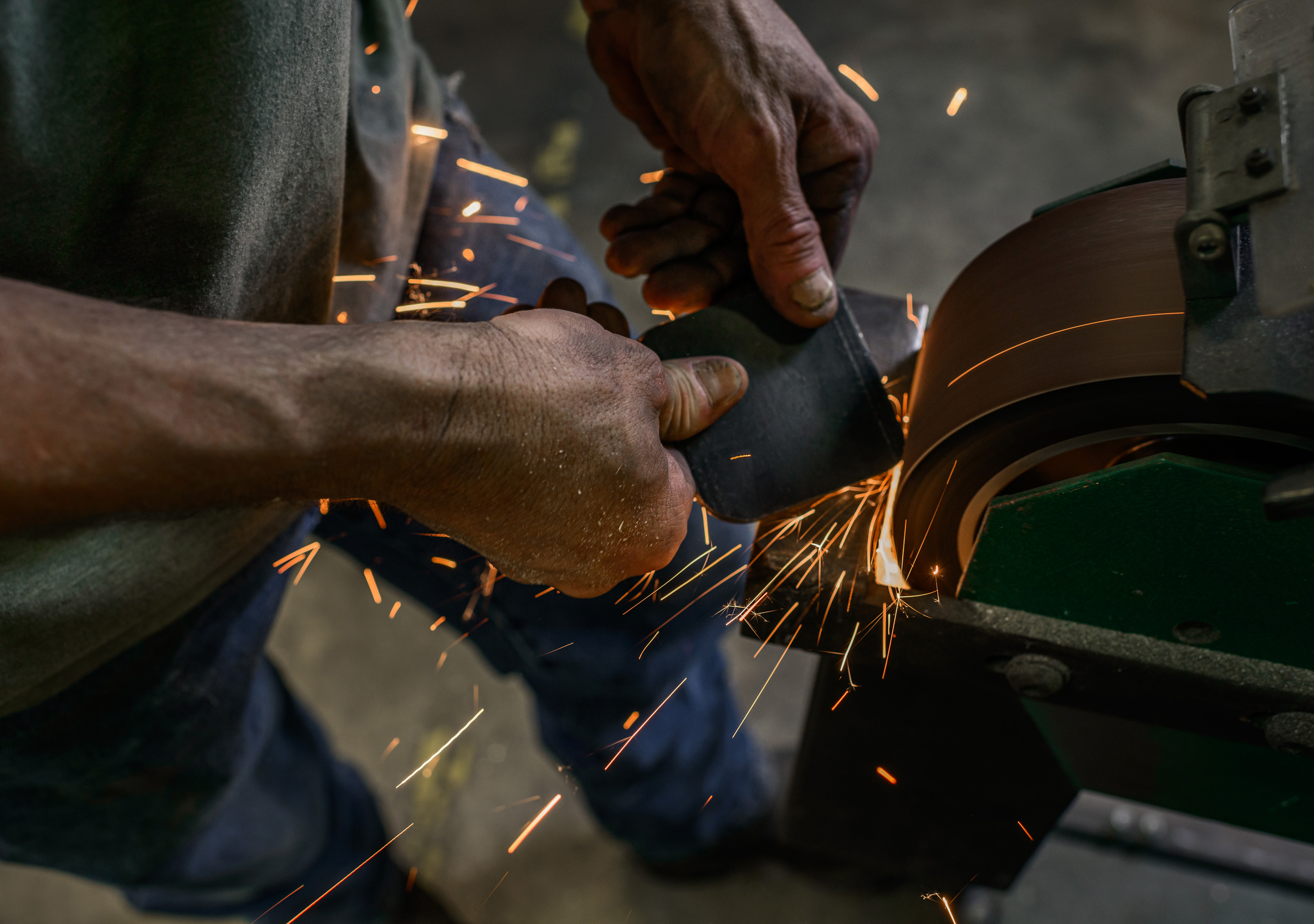 Male hands at work using a grinder in an industrial work shop