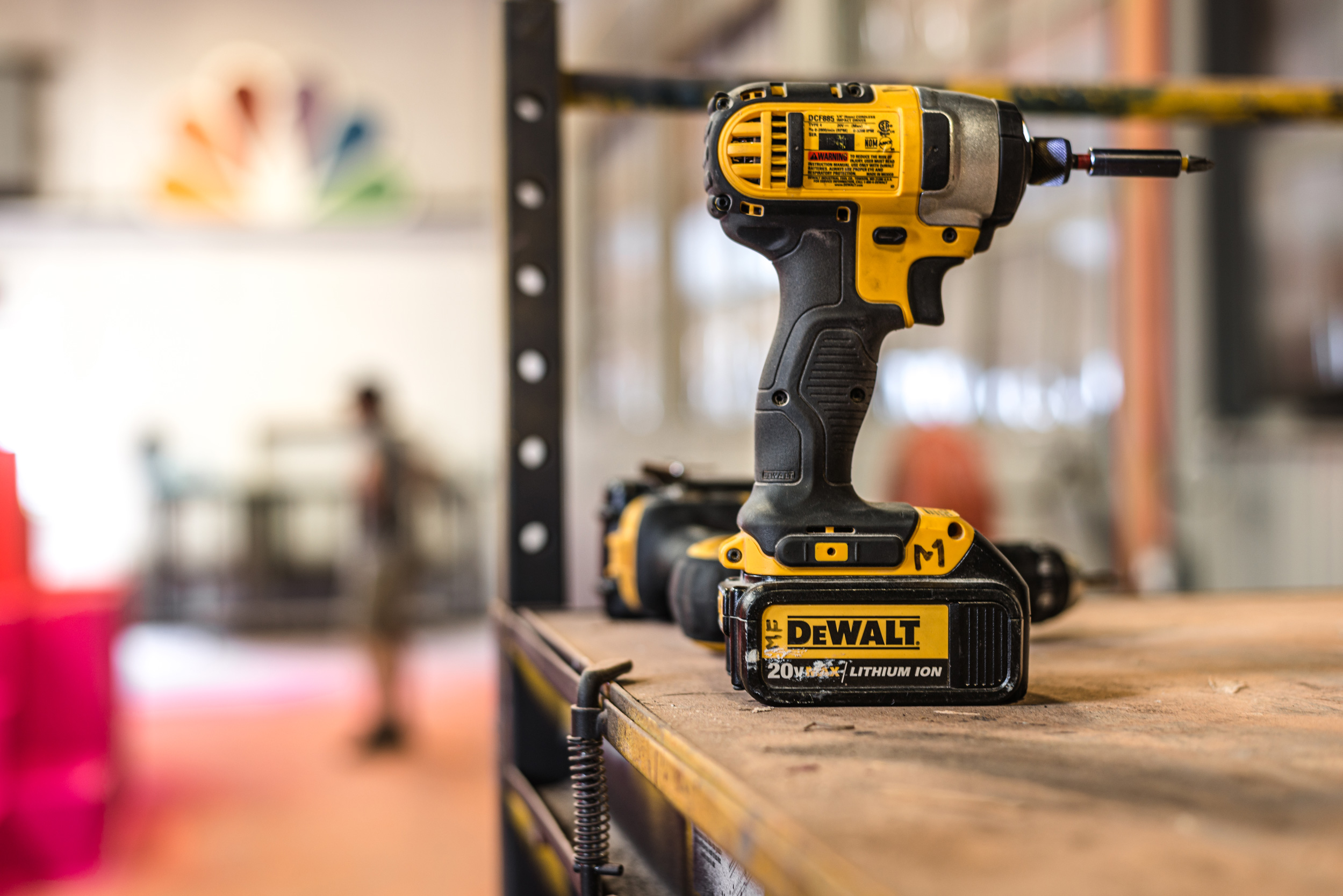 Dewalt drill in workshop with people in background, construction