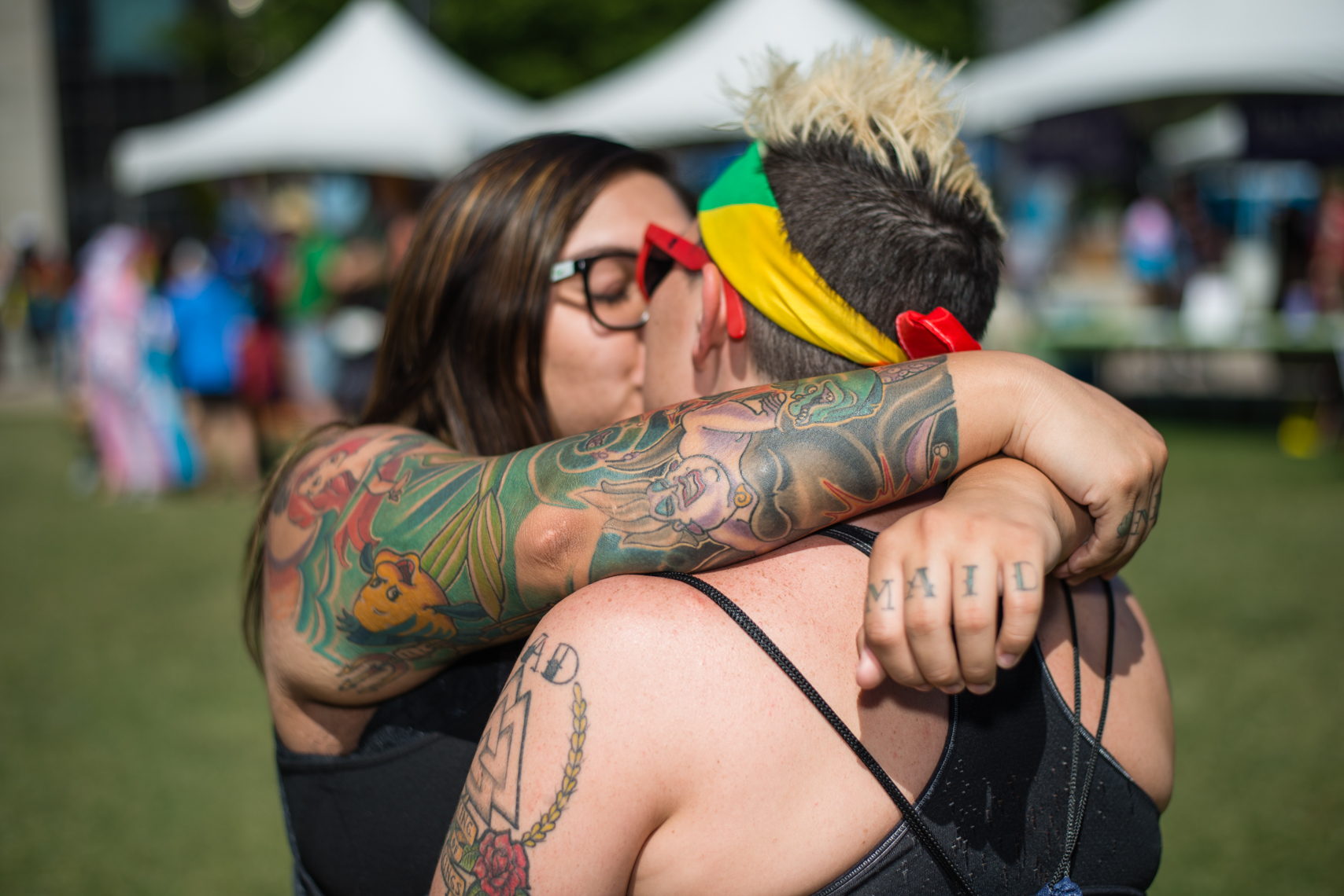 Nashville Pride Festival 2017 | Photographer + Director, Kristina Krug | authentic, authenticity, bisexual, celebrate, celebration, civil, civil liberties, courage, dancing, documentary, drag, emotions, equality, esteem, fearless, festival, festive, free, freedom, friends, fun, gay, happy, journalism, joy, joyful, Kristina Krug, krug photo, lesbian, LGBT, LGBTQ, liberty, love, love wins, loved, love is love, loveliness, lovers, love wins, men, National Pride Day, parade, people, photographer, photojournalism, photojournalist, Portrait, Predators, pride, Pride Parade, proud, queen, queer, relationship, reportage, respect, rights, safety, self, sexuality, summer, sun, sunny, Transgender, women, couple, lesbian couple with tattoos, kissing in a warm embrace at Public Square Park in Nashville, TN