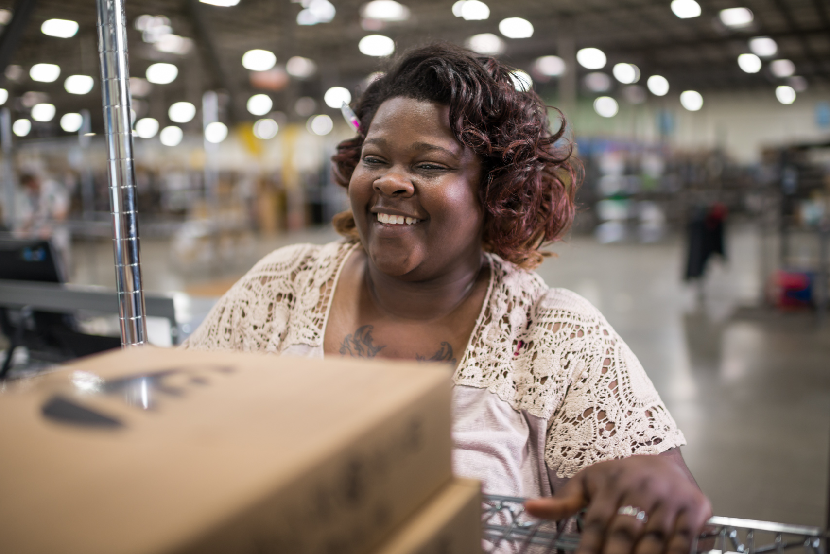 Woman laughing, working, happy, cheerful, rolling a cart through a distribution warehouse. Commercial, corporate, Nashville Photographer, documentary, photojournalist, photo journalist